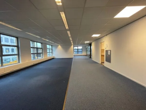 Leeg kantoorpand aan de Rivium 3e Straat met grote ramen en systeemplafond.